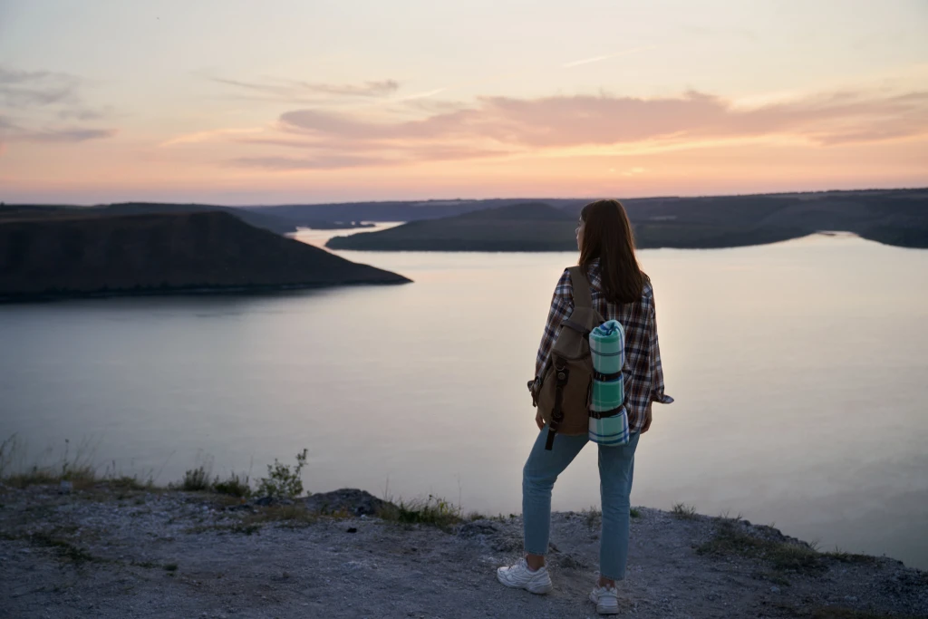 female-traveler-with-backpack-standing-hill-bakota-bay.webp