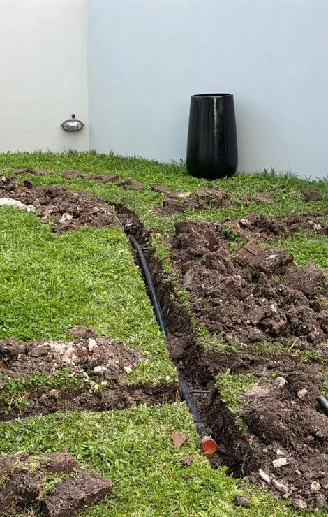 Frente de la casa durante la obra, con la zanja abierta y el caño de riego
