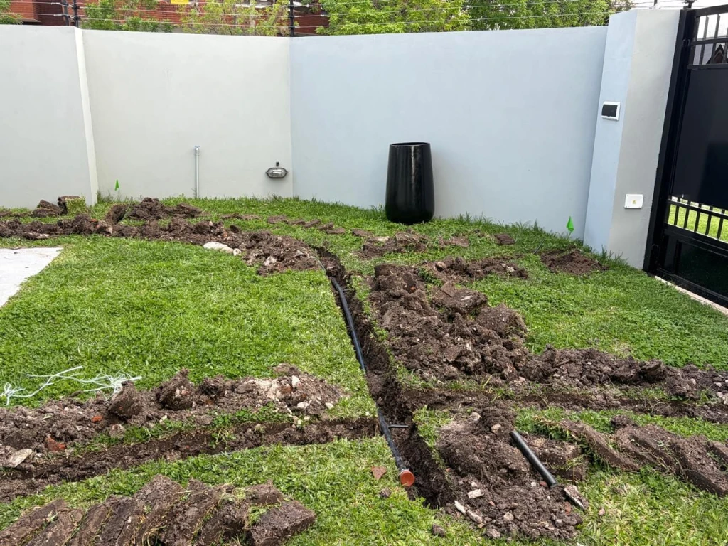 Caño de polietileno tendido en la zanja junto al muro, instalación de riego en Zona Oeste
