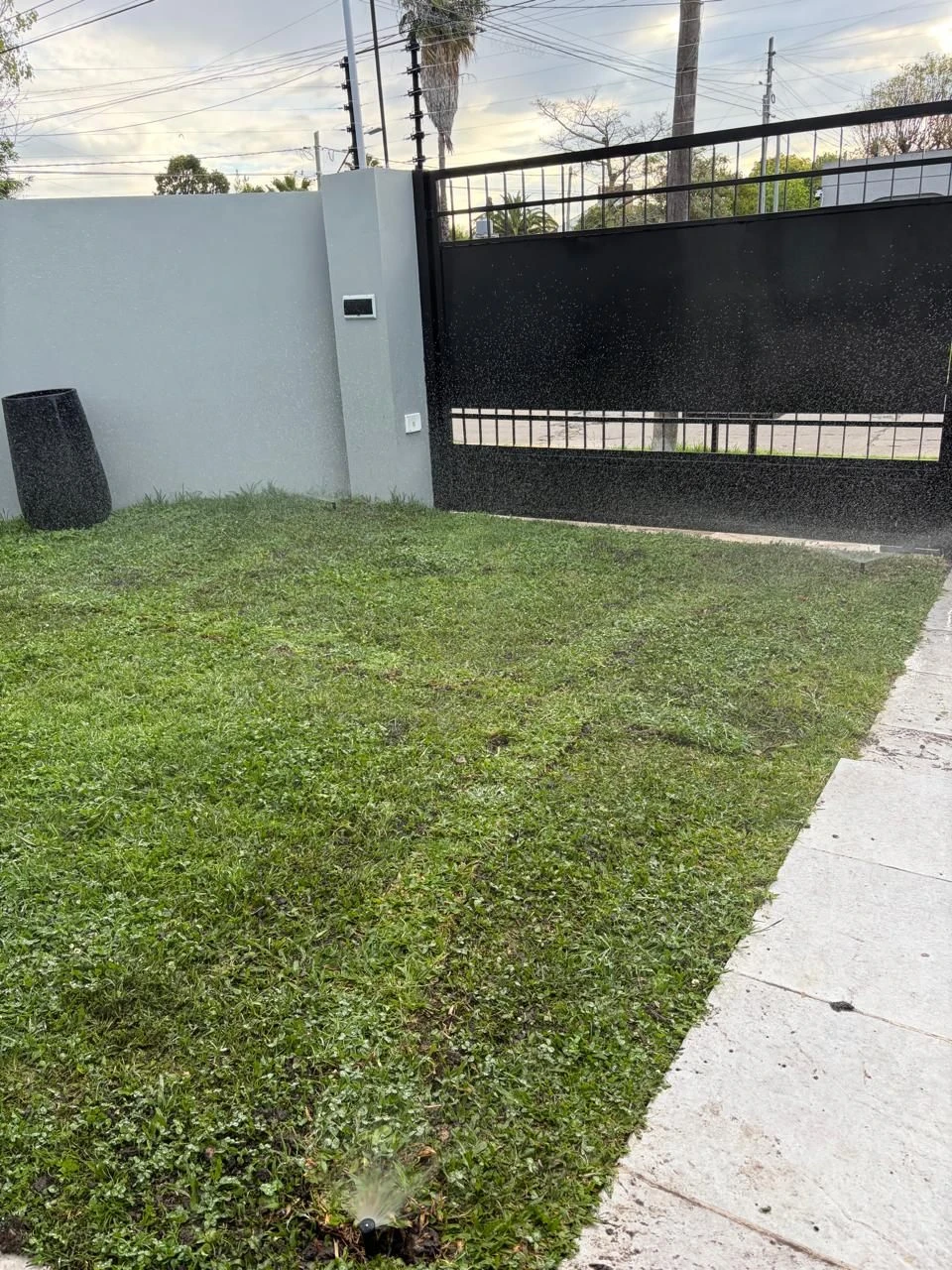 Aspersor emergente regando el césped de una casa en Zona Oeste