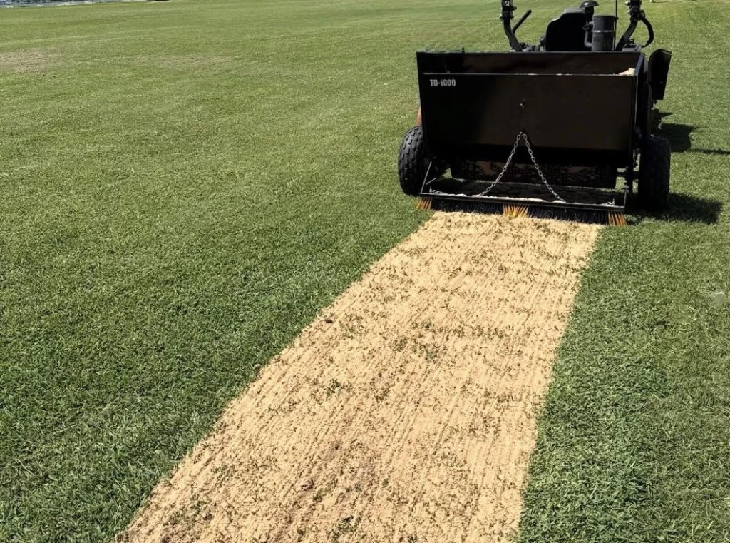 Arenadora haciendo topdressing en una cancha de fútbol