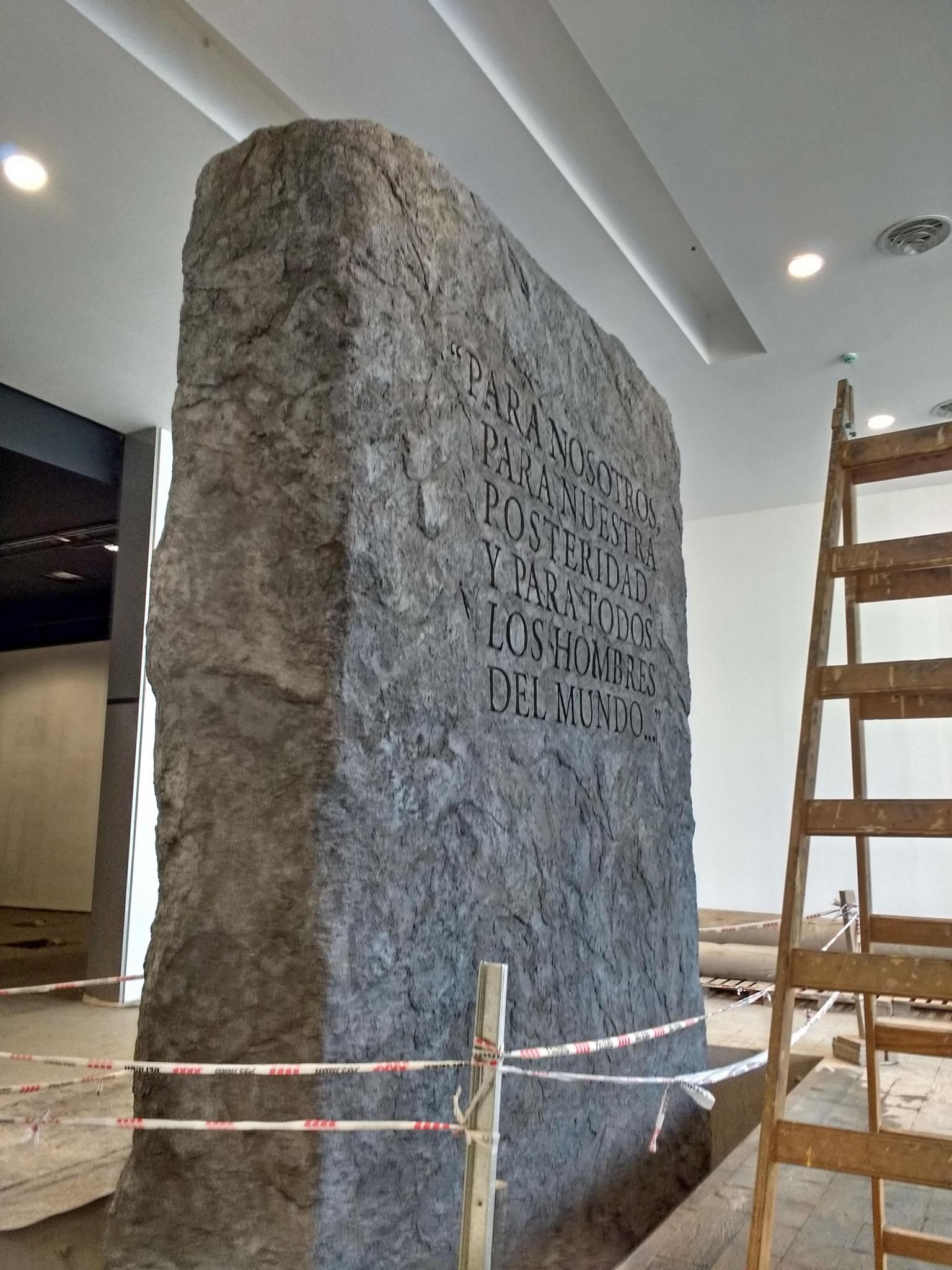Representación de un monolito de granito con las primeras palabras de preámbulo nacional.