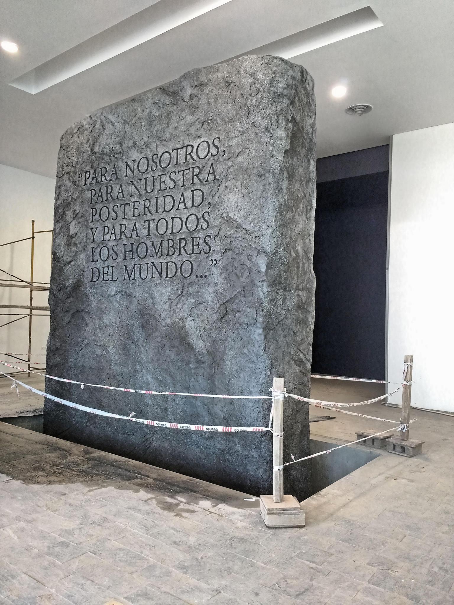 Representación de un monolito de granito con las primeras palabras de preámbulo nacional.