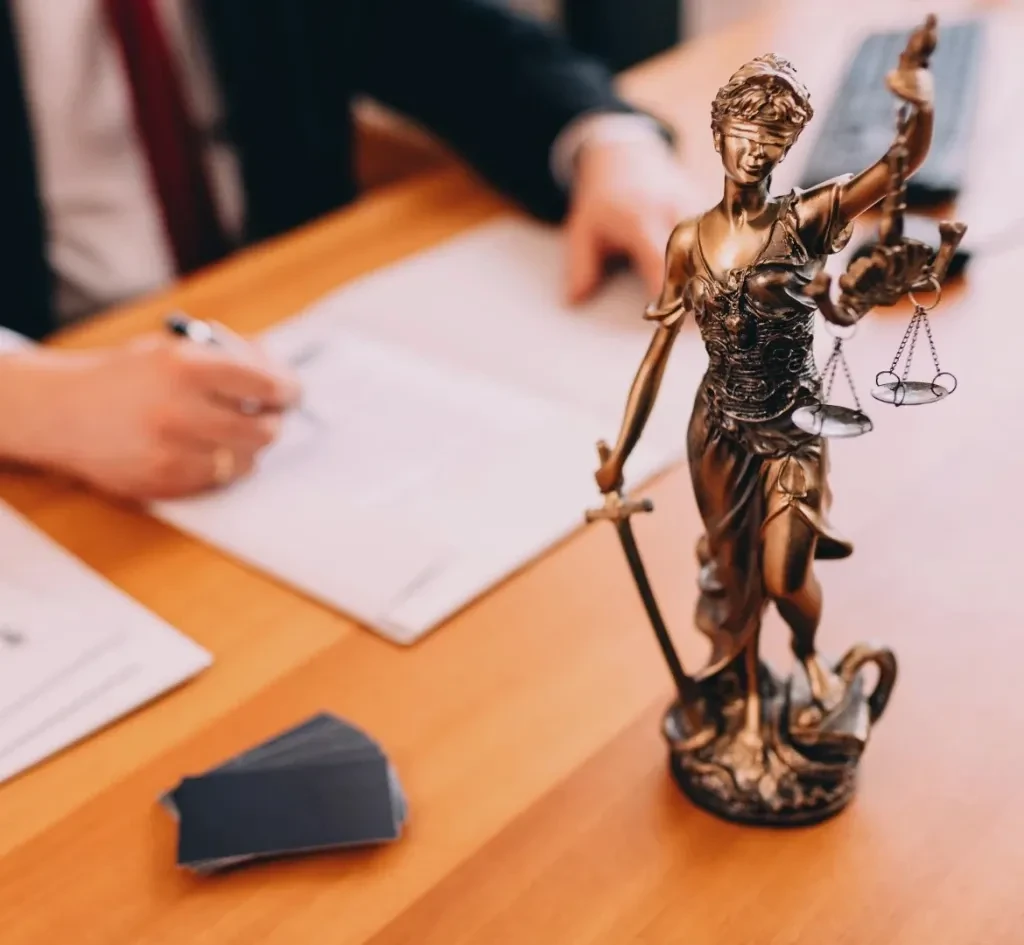 Estatua de la Justicia sobre escritorio jurídico, representando el equilibrio, la imparcialidad y la defensa de derechos.