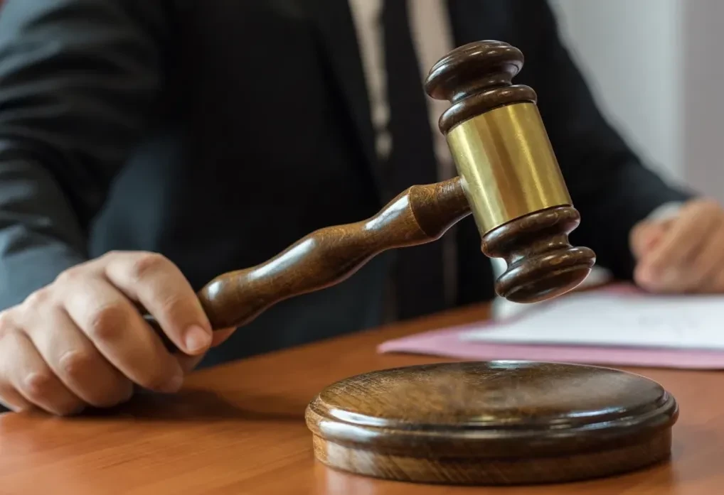 Martillo judicial sostenido por un abogado durante una audiencia, representando la justicia y el ejercicio del derecho