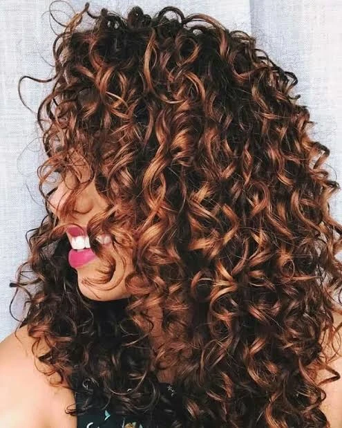 Estilista profesional aplicando productos hidratantes en cabello rizado