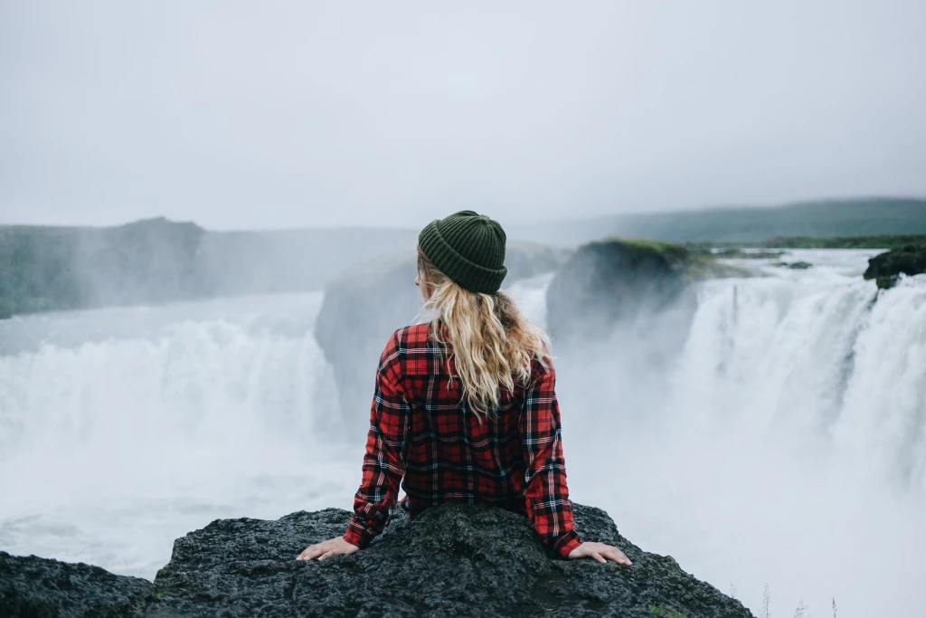 woman-sit-edge-cliff-waterfall.webp