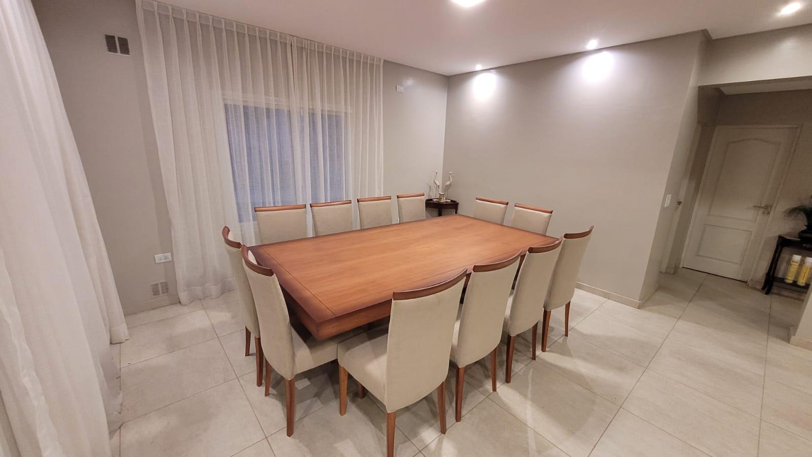 Mesa rectangular rodeada de sillas de respaldo alto junto a cortinas.