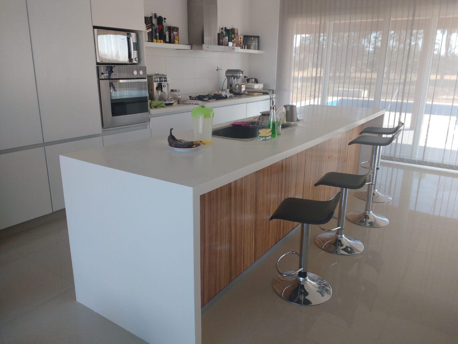 Isla con pie en cascada y mesada de cocina en superficie sólida (corian) sin uniones visibles. Material reparable y antibacteriano, alternativa al silestone marmol y granito. Fabricado por Ai-To en Everlinks Lujan.
