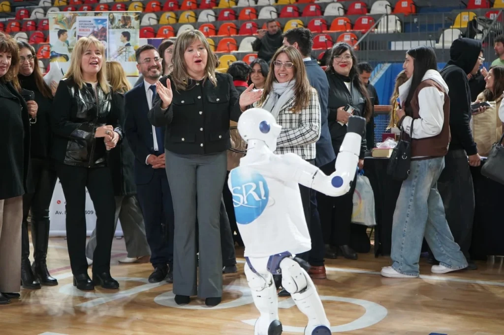 La ministra de Educación de la Provincia, Silvia Fuentes, y la directora de Educación Privada, Andrea Fernández, interactúan con el robot humanoide Unitree R1.